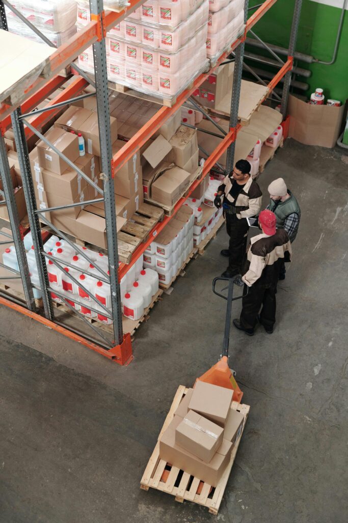 pexels-photo-4481258-4481258 Three warehouse workers discussing inventory organization details.
